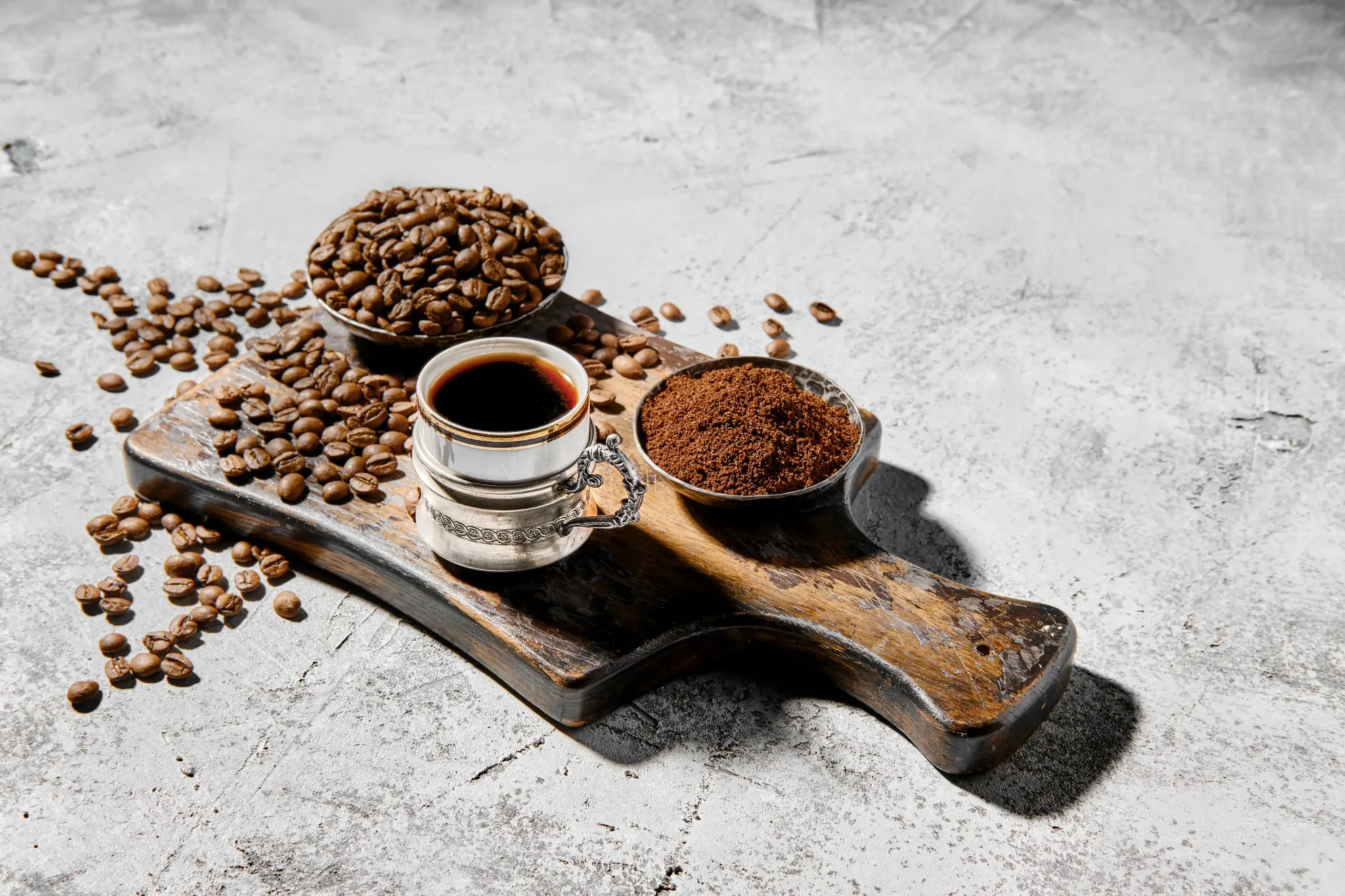 nell'immagine &egrave; raffigurato un tagliere con dei chicchi di caff&egrave;, del caff&egrave; in polvere, e una tazzina di caff&egrave; espresso
